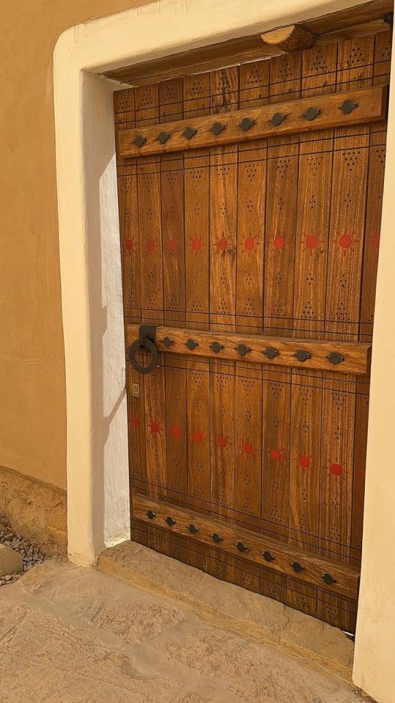 Close-up of a hand-carved wooden door with brass studs, displaying enduring Arabic craftsmanship
