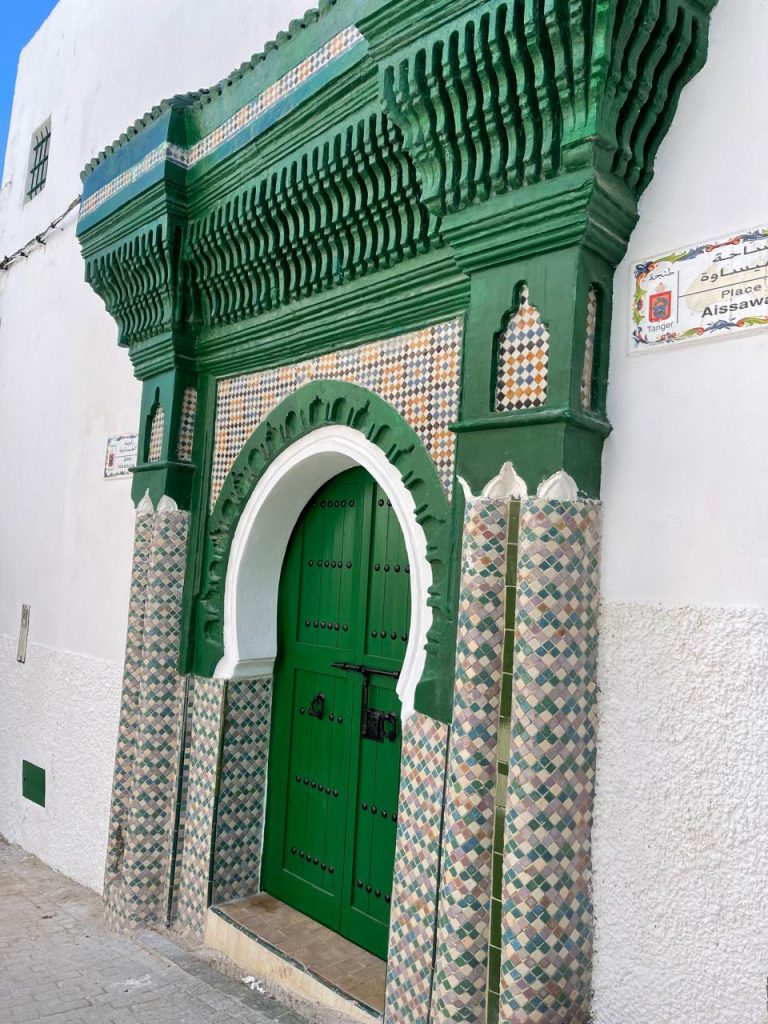 Vivid green door framed by white and green Islamic geometric tiles, adding bold colour to traditional architecture