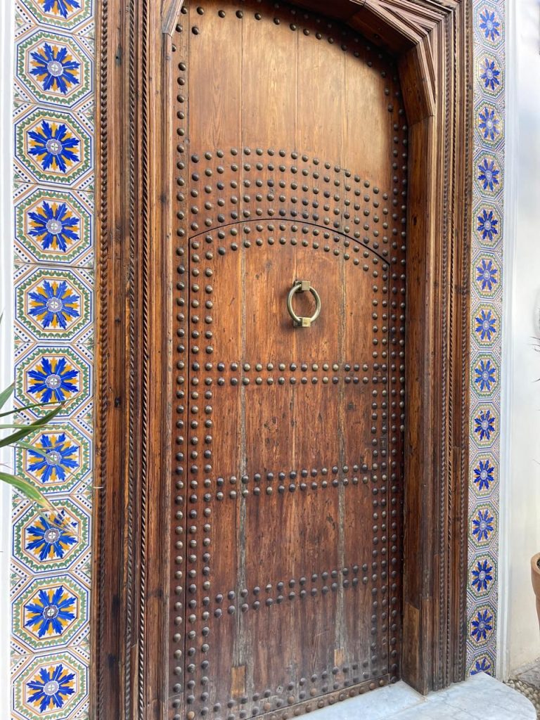 Hand-carved wooden door with decorative blue tilework, reflecting artisanal heritage