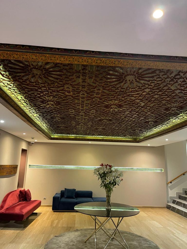 Ceiling of a traditional Arabic majlis, where intricate wooden craftsmanship complements modern furnishings