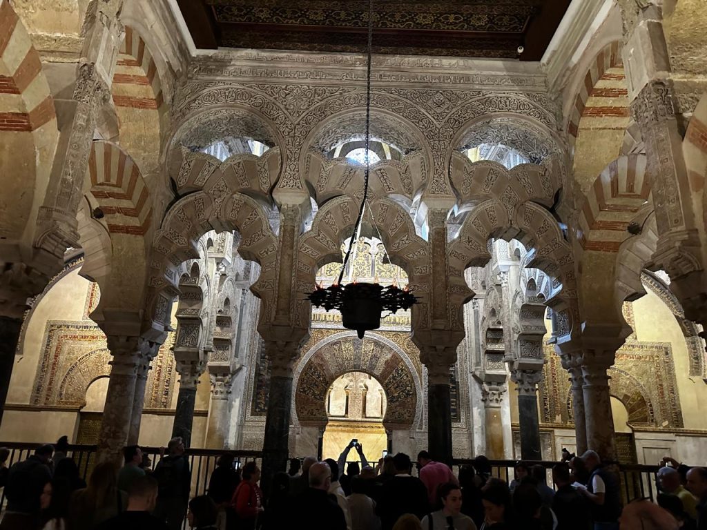 Interior of the Mezquita in Córdoba, featuring ornate arches, calligraphy, and geometric designs.