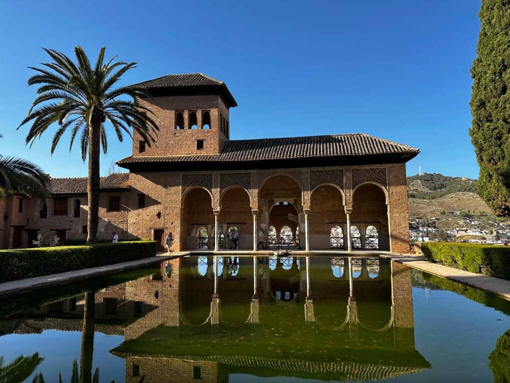 Reflecting pool and arched gallery in the Alhambra courtyard, representing Andalusian elegance.