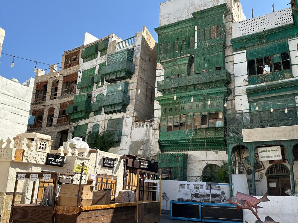 Facade of the Jeddah Academy of Fine Art in Al-Balad, with green wooden mashrabiya balconies and historic Hijazi architecture.