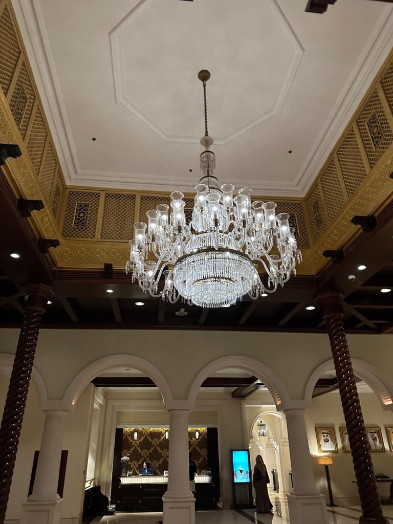 Elegant hotel lobby with ornate chandelier and Islamic-style arches in the ceiling.