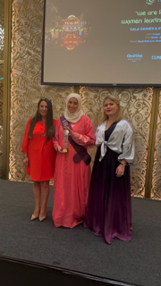 Award ceremony photo: Claire with artist from Iraq in formal celebration
