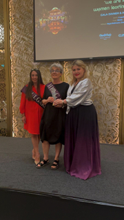 Claire on stage presenting award to honoree from Hungary under gala spotlight

